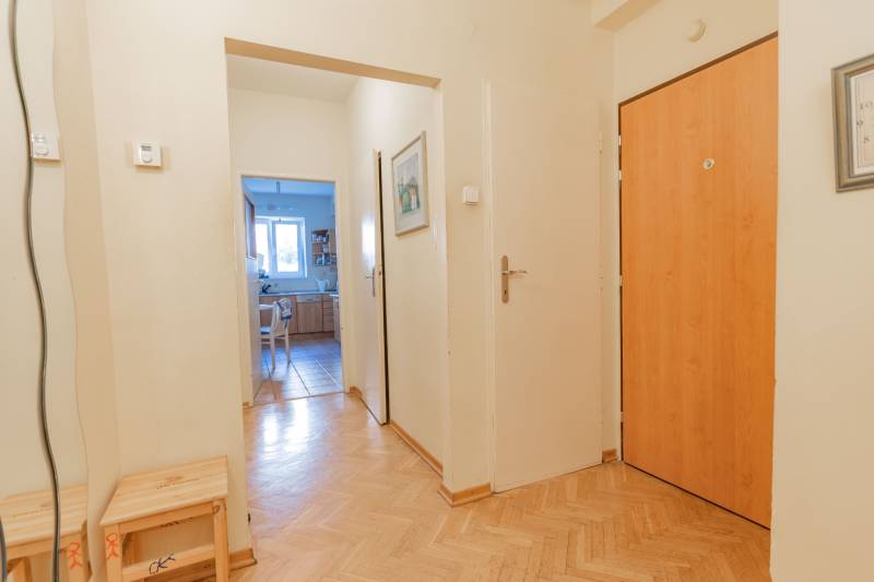 Chodba se vstupem do kuchyně, podlaha s dřevěným dekorem, ve 4pokojovém bytě.
