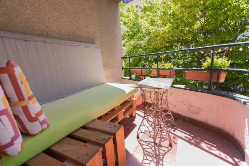 Balkon s dřevěnými paletami a kovovým stolem ve 4pokojovém bytě.