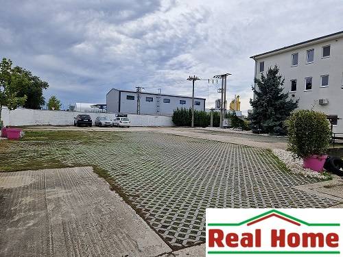 Parkoviště na ulici Šamorínská u skladů a hal, s označením realitní kanceláře.