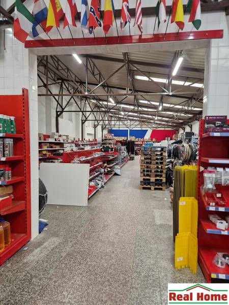 Prodejna na Šamorínské nabízí různé zboží mezi sklady a halami, zavěšené vlajky.