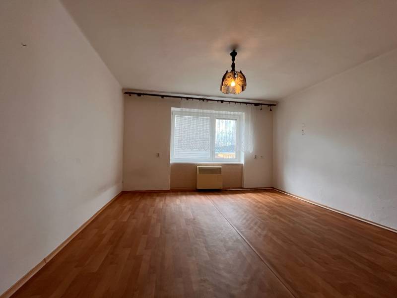 Pokoj s dřevěnou podlahou a závěsným osvětlením v 2-pokojovém bytě.