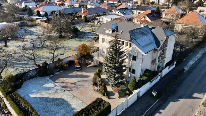 Vila na ulici Sportovců v Topoľčanech, obklopená zelení a bílým plotem.