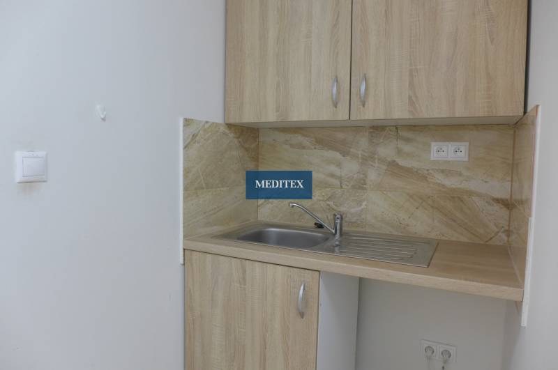 Kuchyňský kout ve skladech a halách s dřevěnými skříňkami a umyvadlem.