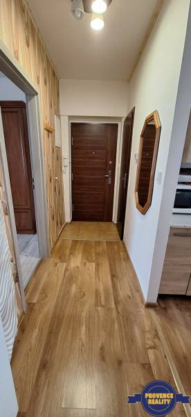 Vstupní hala ve 3-pokojovém bytě s dřevěným obkladem a podlahou.
