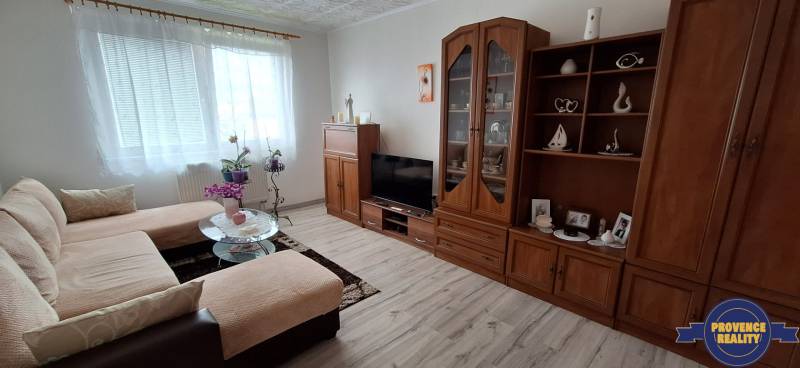 Obývací pokoj v 3-pokojovém bytě s pohovkou, skříňkou a televizorem, světlá dekorace.