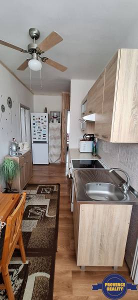 Kuchyně v 3-pokojovém bytě s dřevěným nábytkem a stropním ventilátorem.