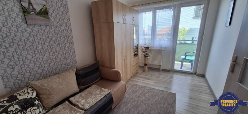 Pokoj v 3-pokojovém bytě s pohovkou, šatníkem a balkonem.