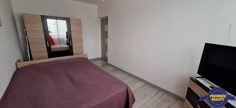 Ložnice s postelí, bílými stěnami a skříní, 3-pokojový byt.