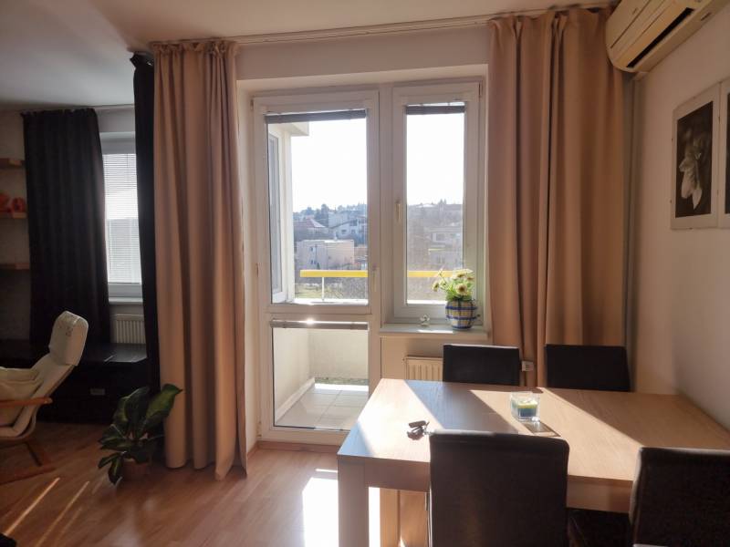 Jídelna ve 4-pokojovém bytě s přístupem na balkon a výhledem na město.