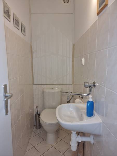 Malá koupelna ve 4-pokojovém bytě s toaletou, umyvadlem a světlou dlažbou.