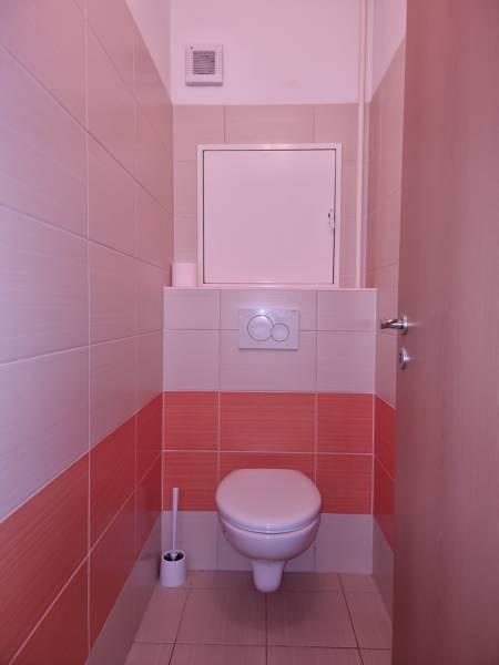 Toaleta s dlaždicemi v oranžovo-bílé kombinaci v 2-pokojovém bytě.