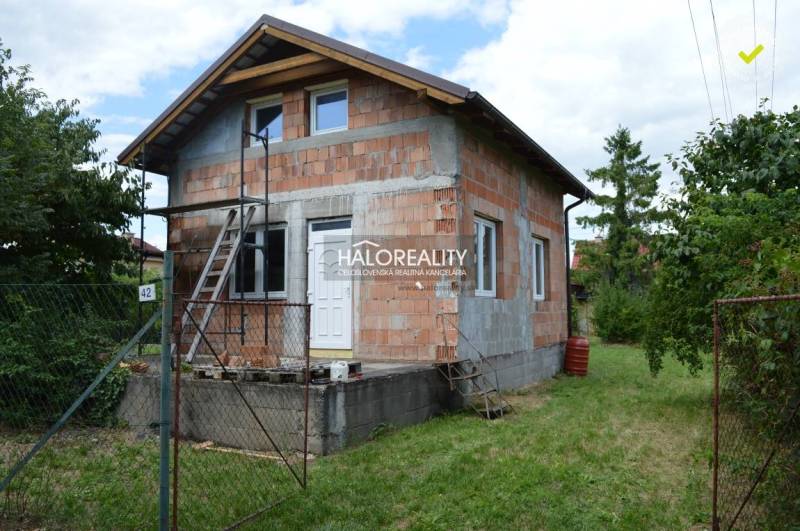 Chata ve Vinosadech postavená z cihel, s žebříkem a zeleným okolím.