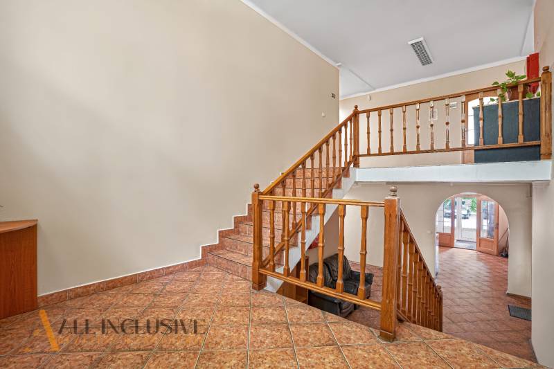 Interiér kanceláře s dřevěným schodištěm a dlažbou na podlaze.