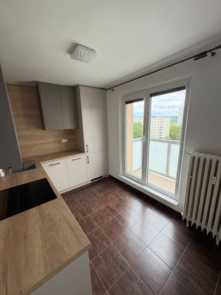 Kuchyně v 2-pokojovém bytě s dřevěnou pracovní deskou a přístupem na balkon.