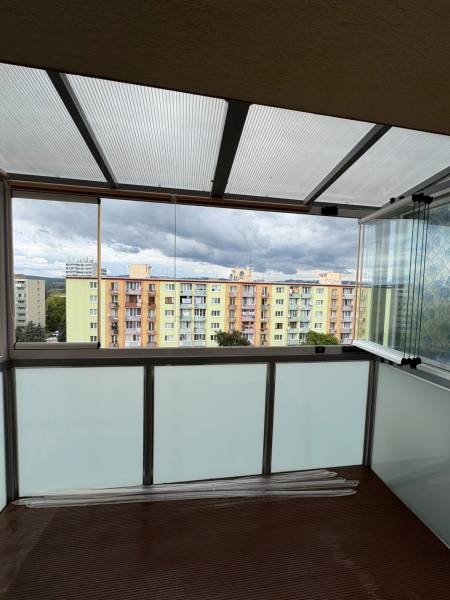 Zasklený balkon s výhledem na barevné bytovky v Nové Dubnici na ulici SNP.