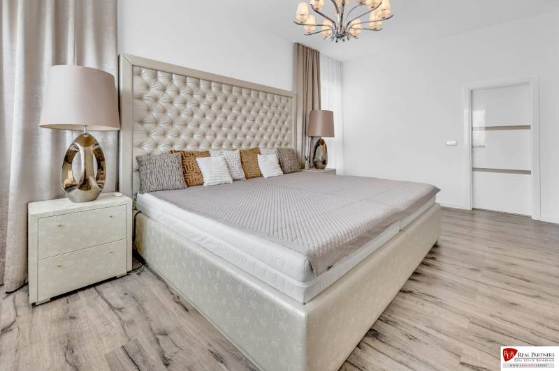 Luxusní ložnice s velkou postelí a stylovým lustrem ve 4pokojovém bytě.