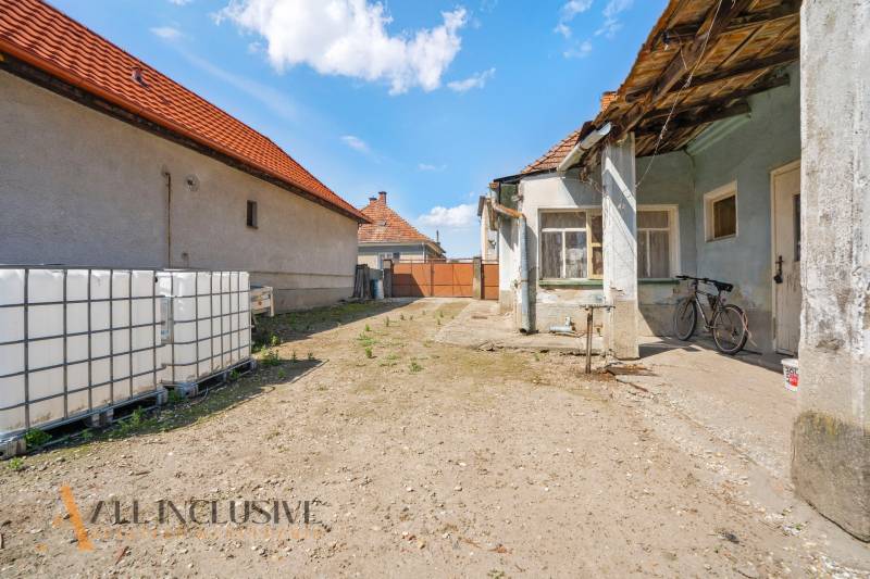 Dvůr rodinného domu v Jahodné s kolem a velkými nádržemi na vodu.