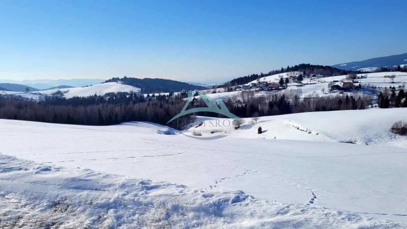 Zasněžená krajina s kopci a lesy, ideální lokalita pro bydlení. Pozemky krásně viditelné.