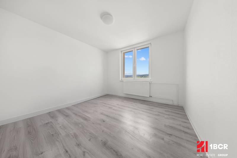 Prázdný pokoj v 2-pokojovém bytě s oknem a dřevěnou podlahou.