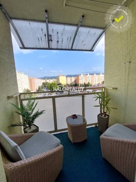 Balkon 3-pokojového bytu s ratanovým nábytkem a výhledem na sídliště v Prievidzi.