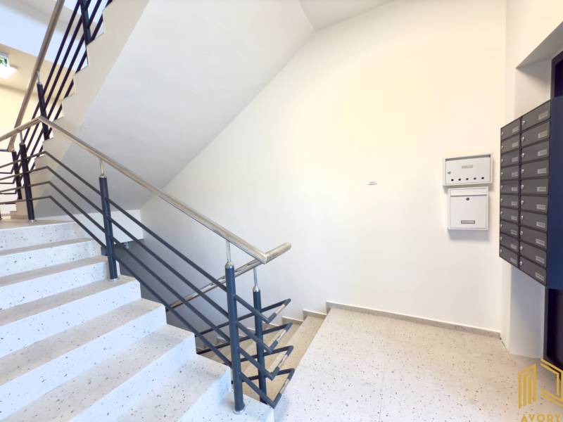 Předsíň v garsonce s poštovními schránkami a schodištěm.