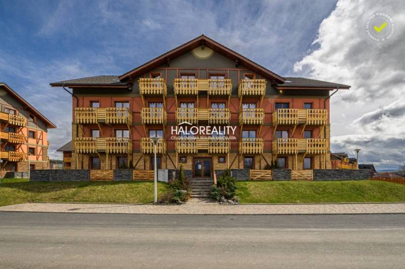 Exteriér vícepodlažní budovy s dřevěnými balkóny v obci Velká Lomnica.
