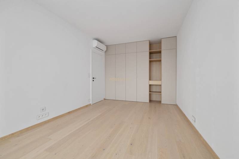 Prázdný pokoj s dřevěnou podlahou, vestavěnou skříní a klimatizací v 2-pokojovém bytě.