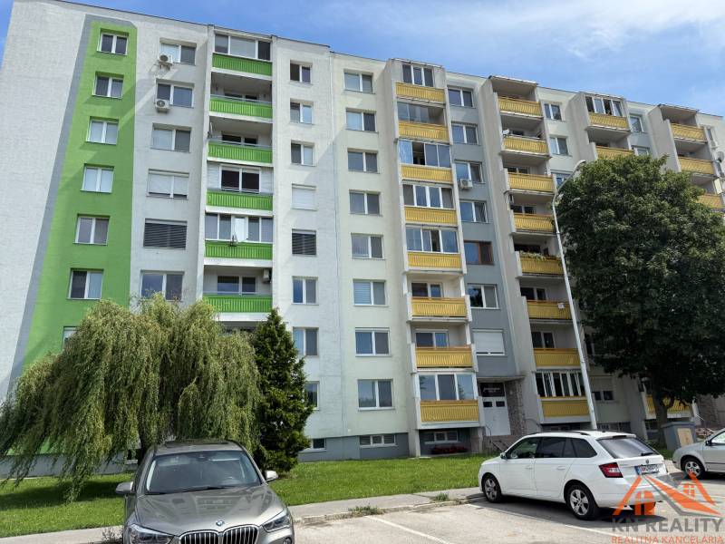 Bytový dům na Železiarenské ulici v Galantě se zaparkovanými auty a zelení.