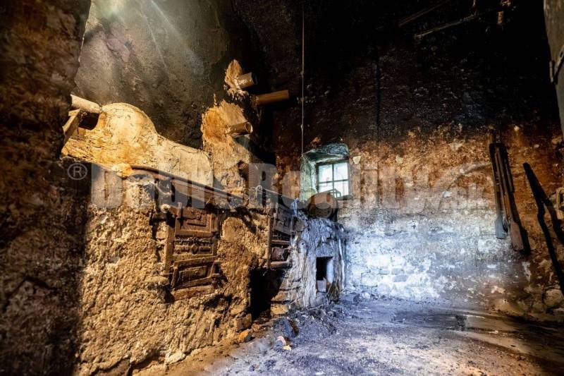 Opuštěné a znečištěné prostory v rodinném domě s viditelnými kovovými dveřmi pece.