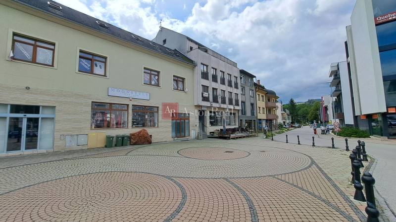 Budova na Mostní ulici v Ružomberku s dlážděným náměstím a okolní infrastrukturou.