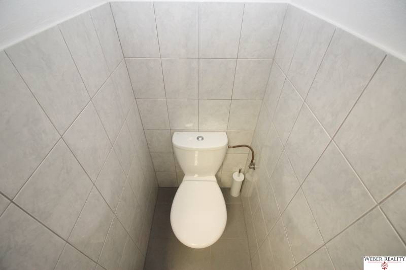Toaleta s bílým obkladem v obchodních prostorách.
