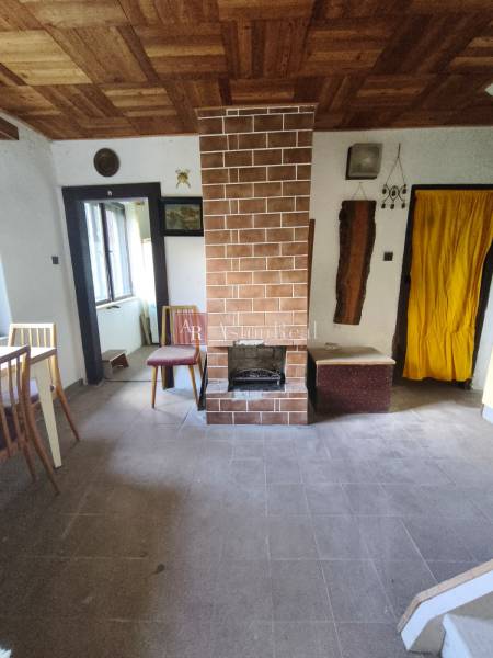 Interiér chaty s krbem, oknem a podlahou s dřevěným dekorem.