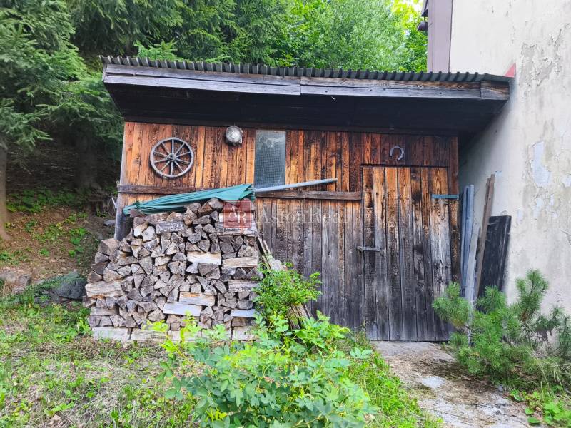 Dřevěná chata v lese na Kordících v Banské Bystrici s uloženým dřevem.