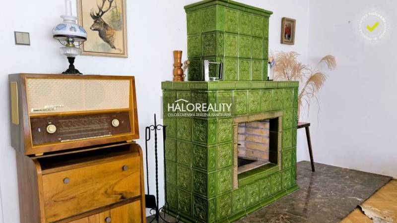 Zelená kachlová kamna, vintage rádio a dekorace v interiéru rodinného domu.