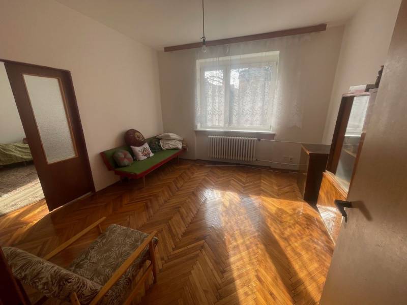 Dřevěné parkety ve světlé místnosti rodinného domu s pohovkou a křeslem.