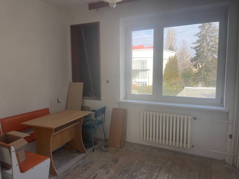 Interiér rodinného domu s oknem, stolem a oranžovou lavicí.