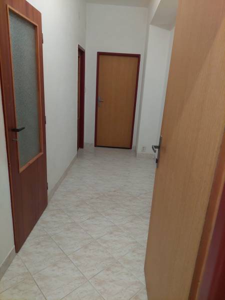 Chodba v rodinném domě s dlažbou a dřevěnými dveřmi.
