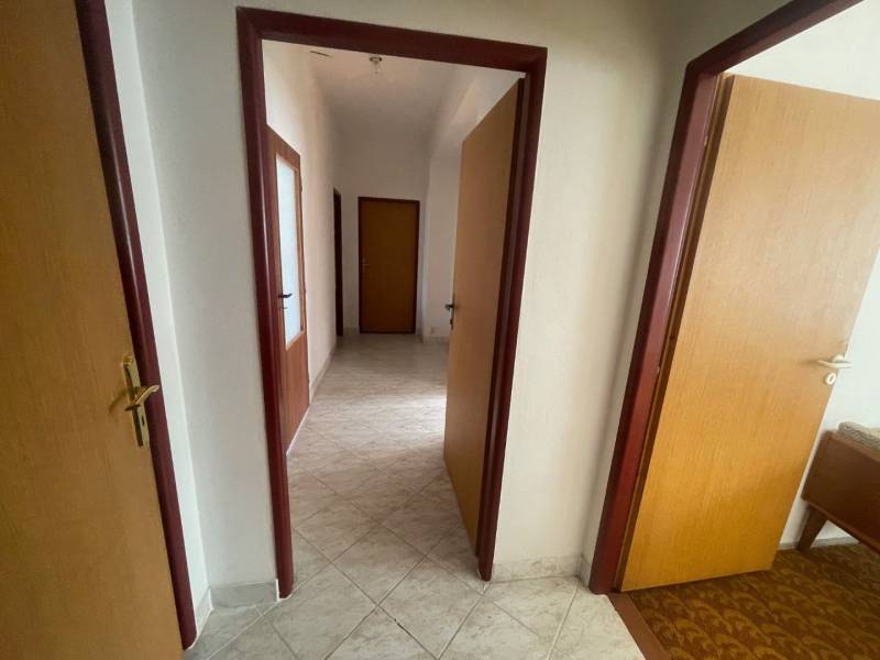 Interiér rodinného domu s chodbou, dveřmi a světlými dlaždičkami.