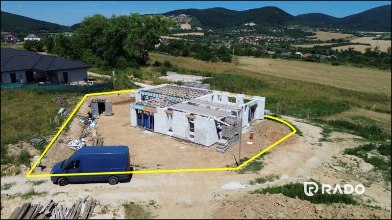 Stavba rodinného domu v Trenčianskom Jastrabí, obklopená zelení a kopci.