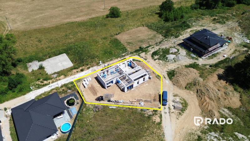 Stavba rodinného domu v Trenčianskom Jastrabí, obklopená přírodou a dalšími stavbami.