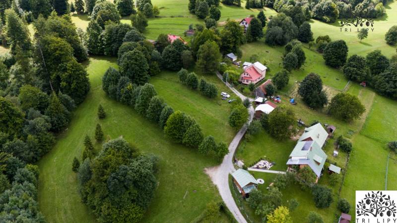 Letecký pohled na rekreační pozemky v Oščadnici obklopené hustou zelení a domy.