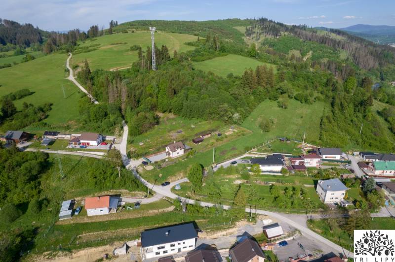 Letecký pohled na pozemky pro bydlení v Rakové, obklopené zelenými kopci a domy.