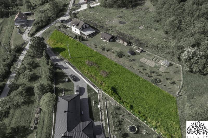 Letecký pohled na pozemky vhodné k bydlení v Rakové, obklopené zelení a domy.