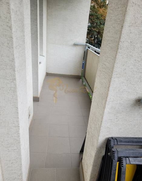 Úzký balkon v 3-pokojovém bytě se zábradlím a dlažbou.