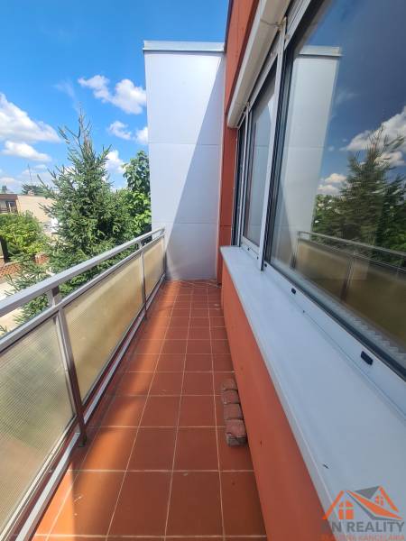 Balkon rodinného domu v Nových Zámcích s dlažbou a výhledem na stromy.