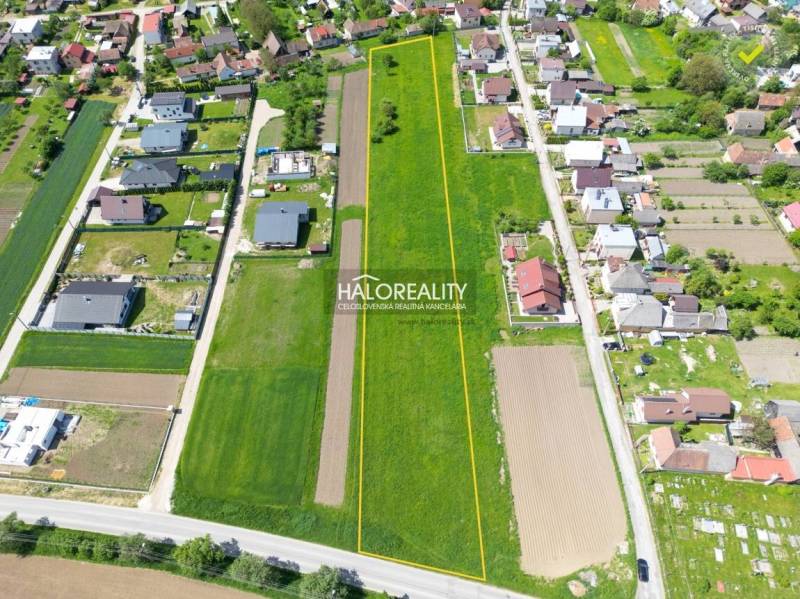 Letecký pohled na pozemky vhodné k bydlení v Udiči, obklopené domy a zelení.
