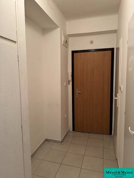 Chodba se světlou dlažbou a dřevěnými dveřmi v 2-pokojovém bytě.