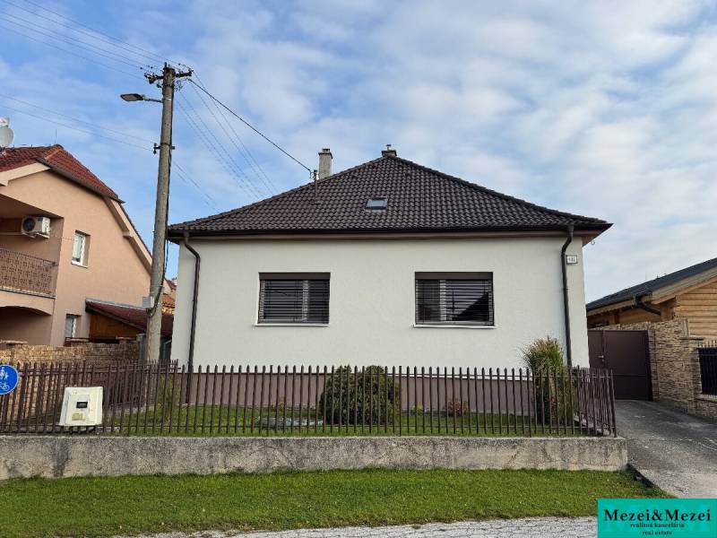 Rodinný dům v Trstíně se šikmou střechou, oplocení a travnatá plocha před domem.