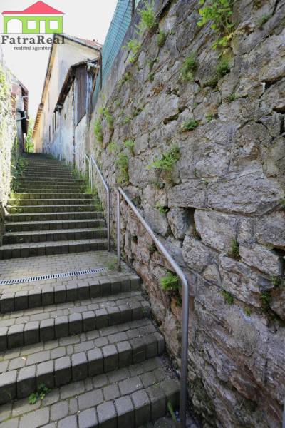 Kamenné schody vedoucí nahoru u budovy na ulici Nám. A. Hlinku.