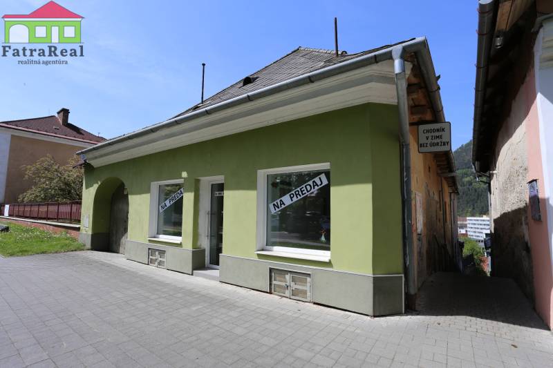 Rodinný dům na ulici Nám. A. Hlinku, určený k prodeji, s nápisem a zelenou fasádou.